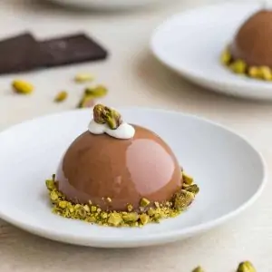 Chocolate Pistachio Dome on a white plate.