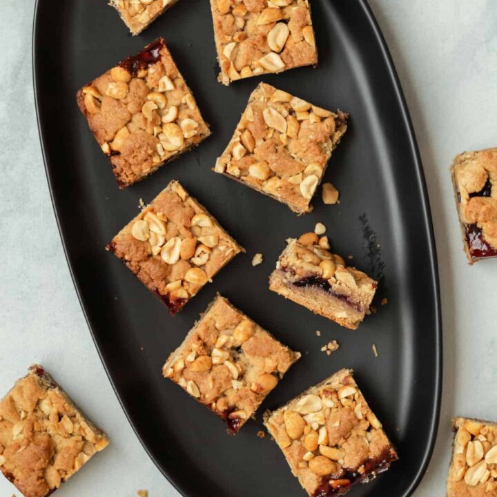 Peanut butter and jelly bars on a black plate with one bar on its side to show the filling.