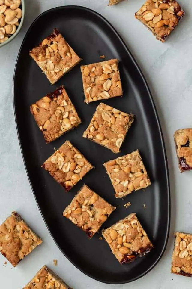 Peanut butter and jelly bars on a black plate.