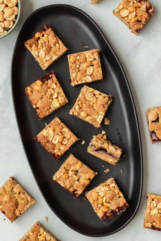 Peanut butter and jelly bars on a black plate with one bar on its side to show the filling.