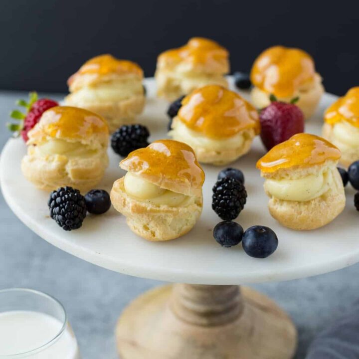 Classic Profiteroles filled with pastry cream on a cake platter