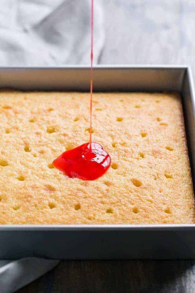 angled view of strawberry syrup poured over vanilla cake