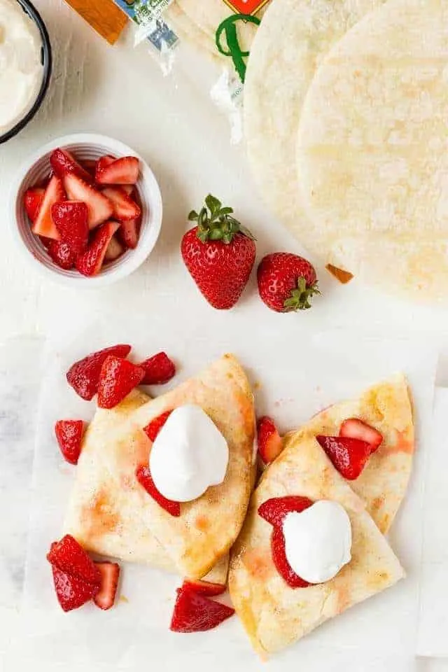 Overhead view of fresh strawberries and cream cheese stuffed inside flour tortillas,