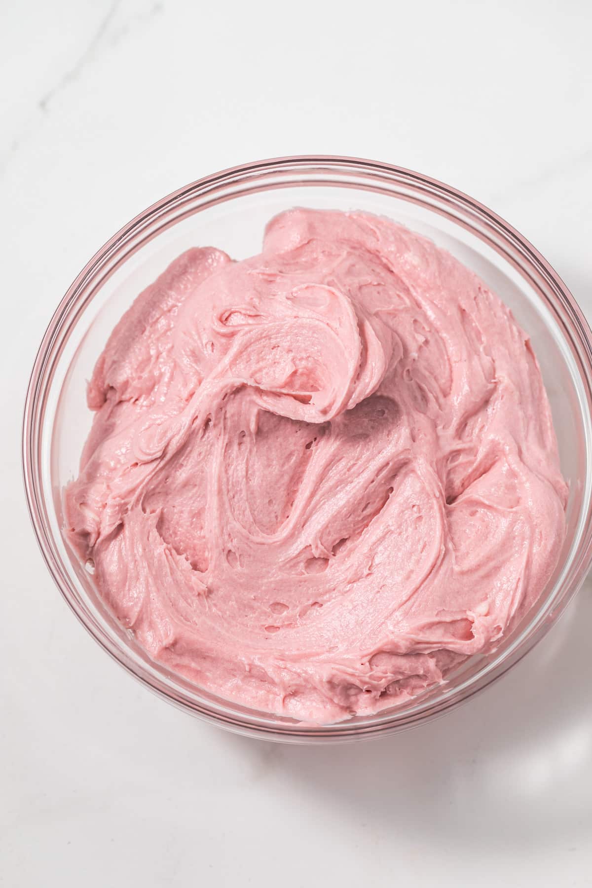 Raspberry frosting in a glass bowl.