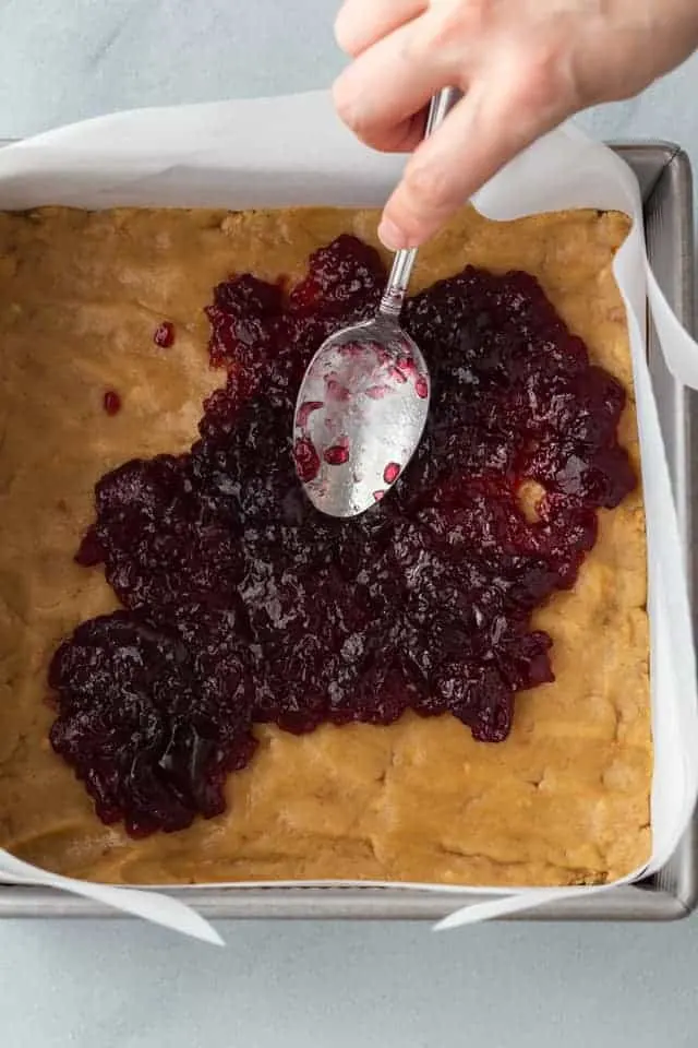 Jelly spread over peanut butter bar batter in a pan