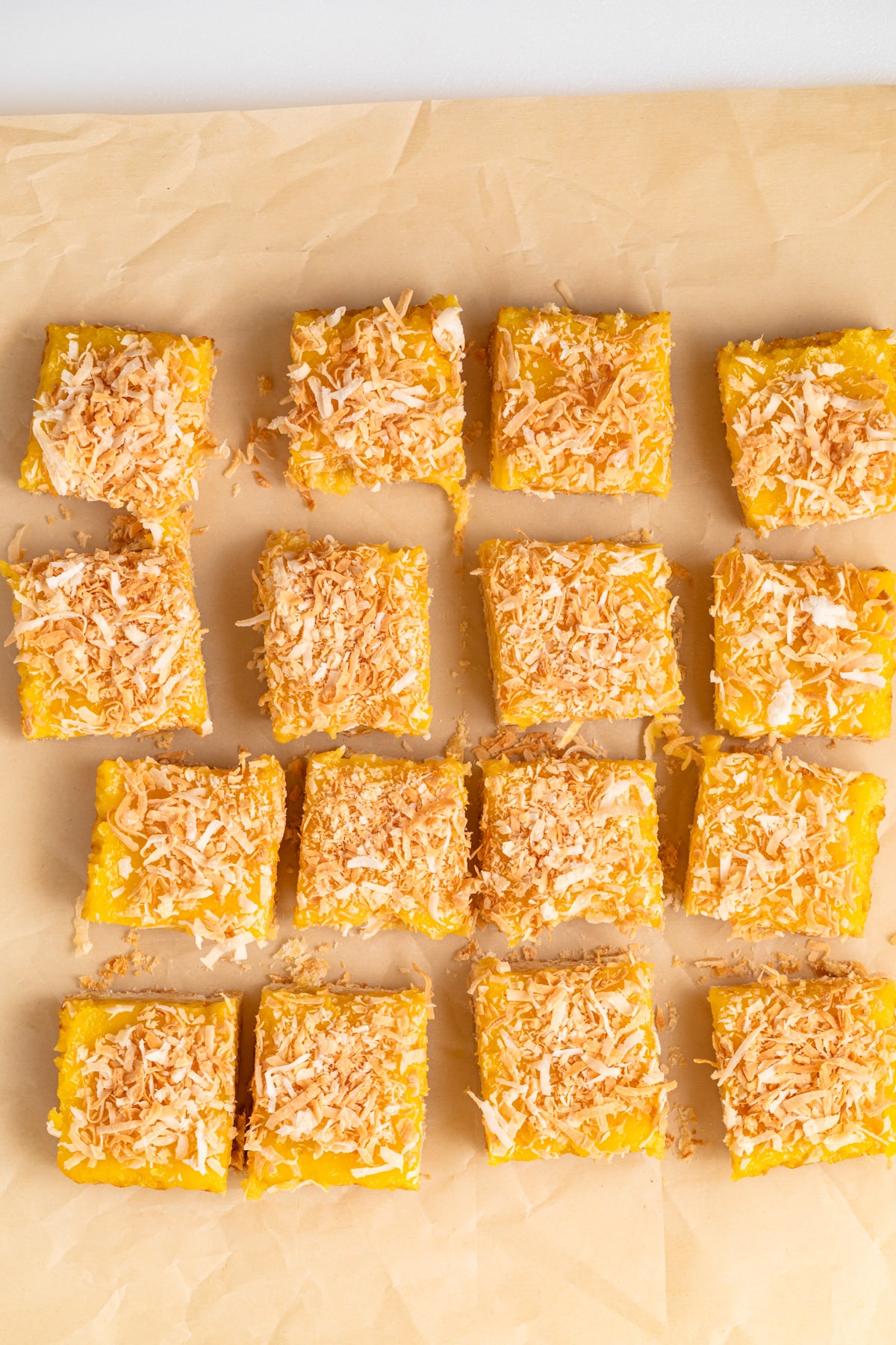 Coconut lemon bars on parchment paper.