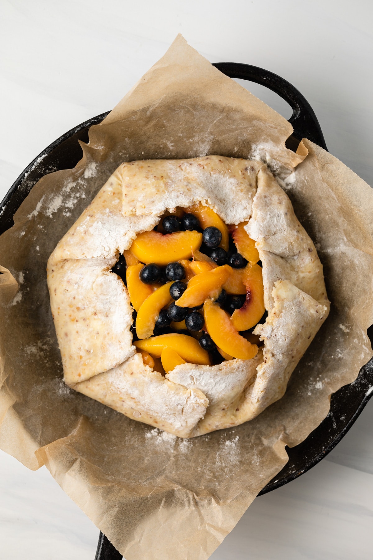 Unbaked peach blueberry galette in cast iron skillet.