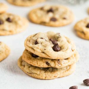 Three Chewy Chocolate Chip Cookies stacked on a white background.