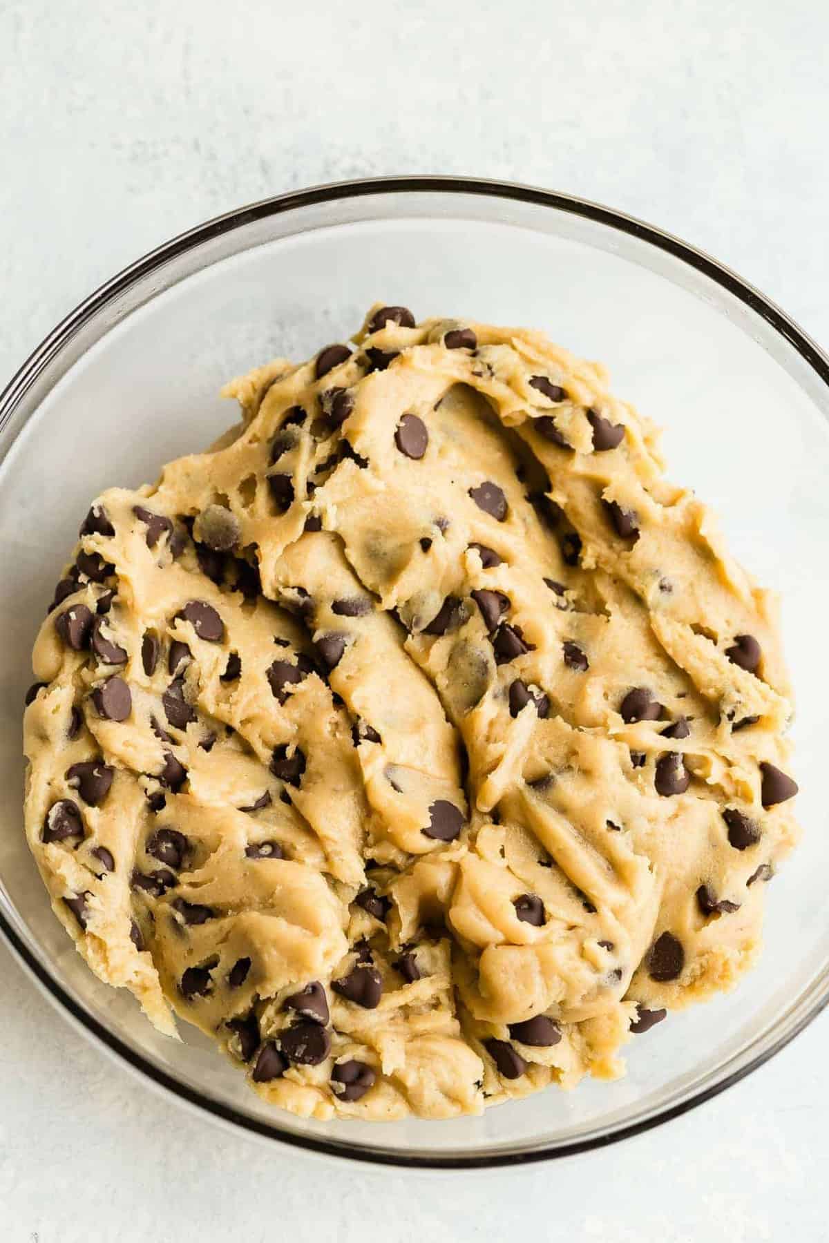 Chewy chocolate chip cookie dough in a glass bowl.