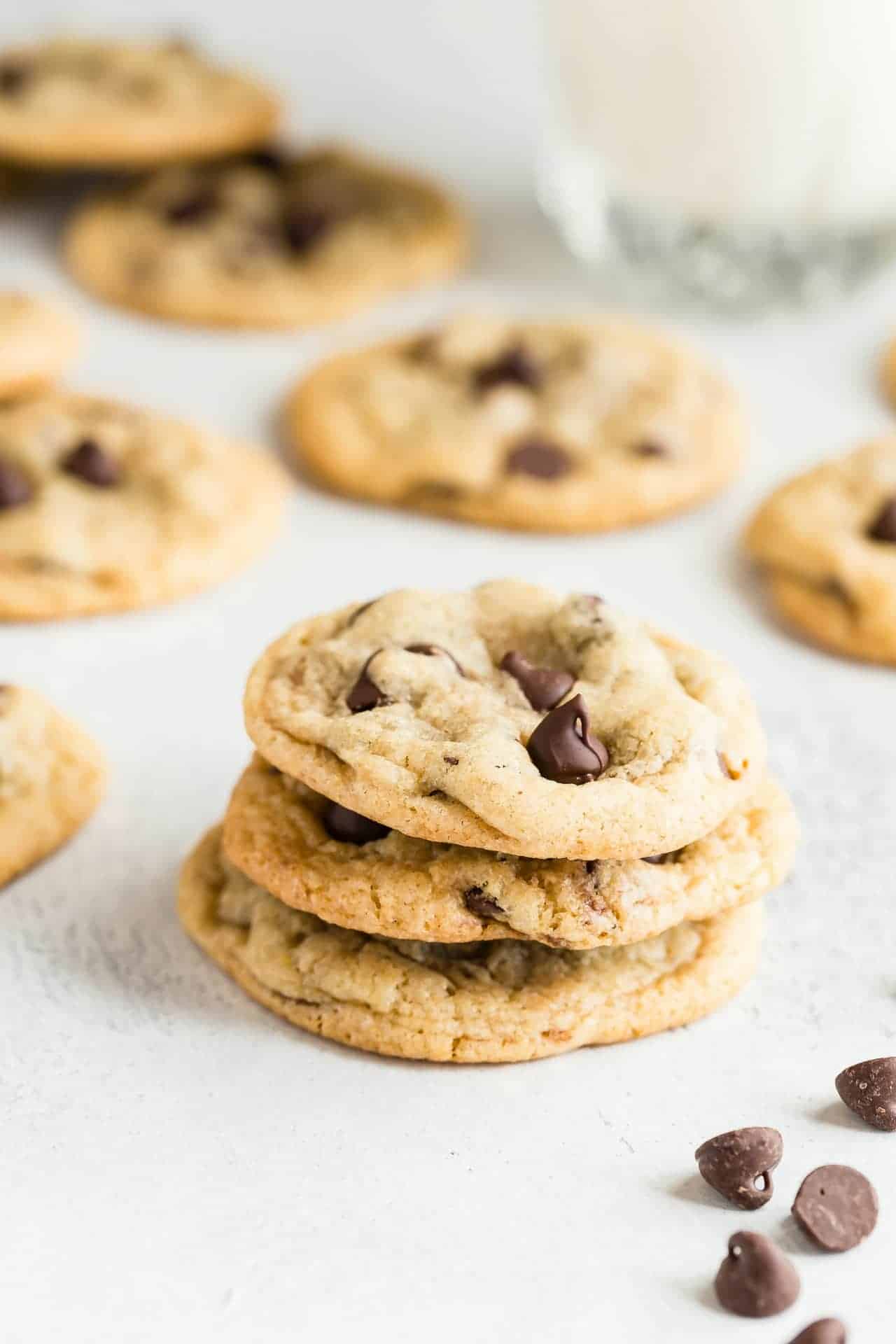 Three Chewy Chocolate Chip Cookies stacked on a white background.