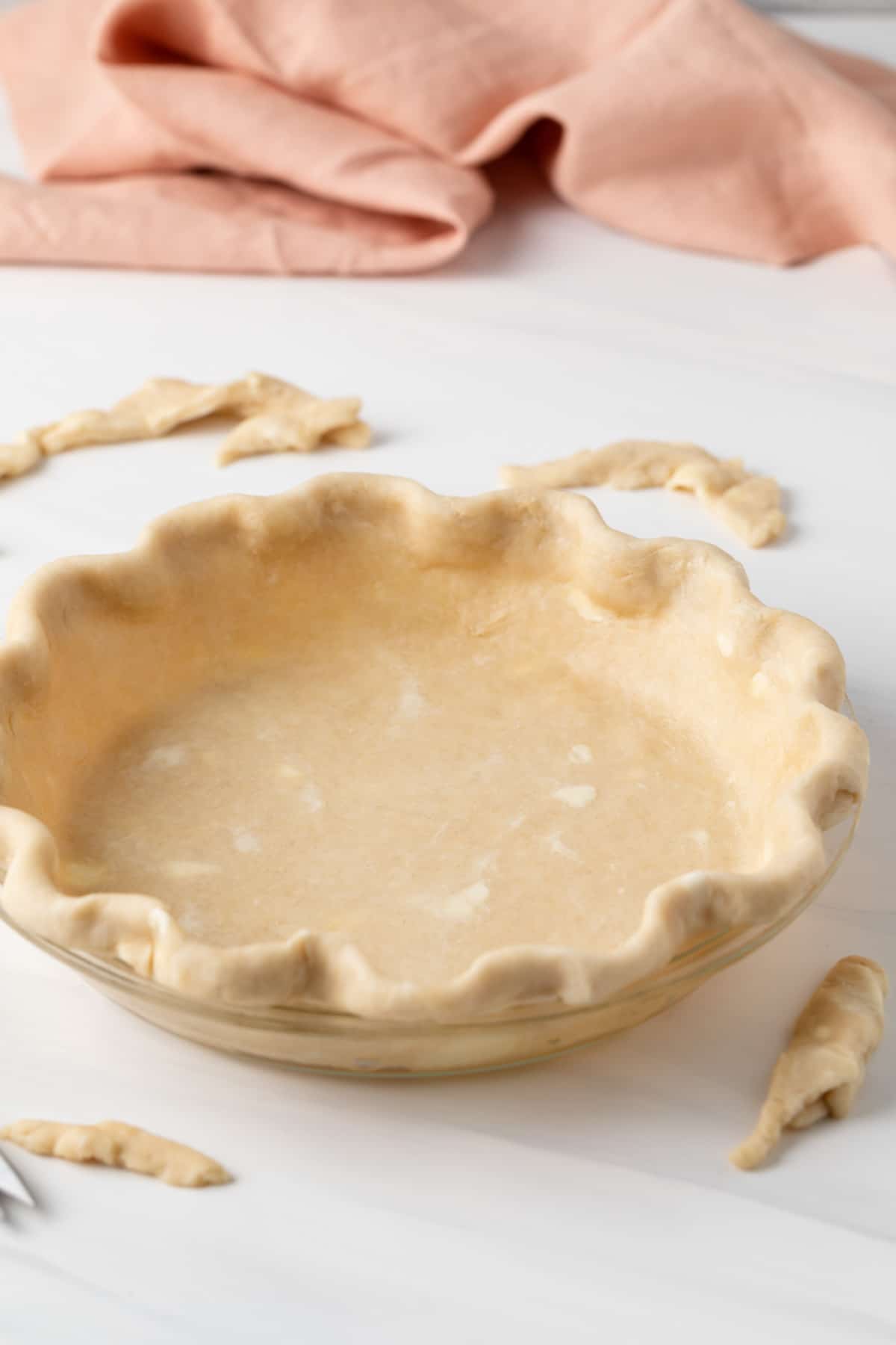 side view of unbaked pie crust in glass pie pan