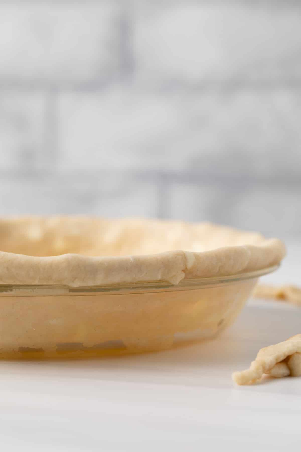 side view of unbaked pie crust in glass pan