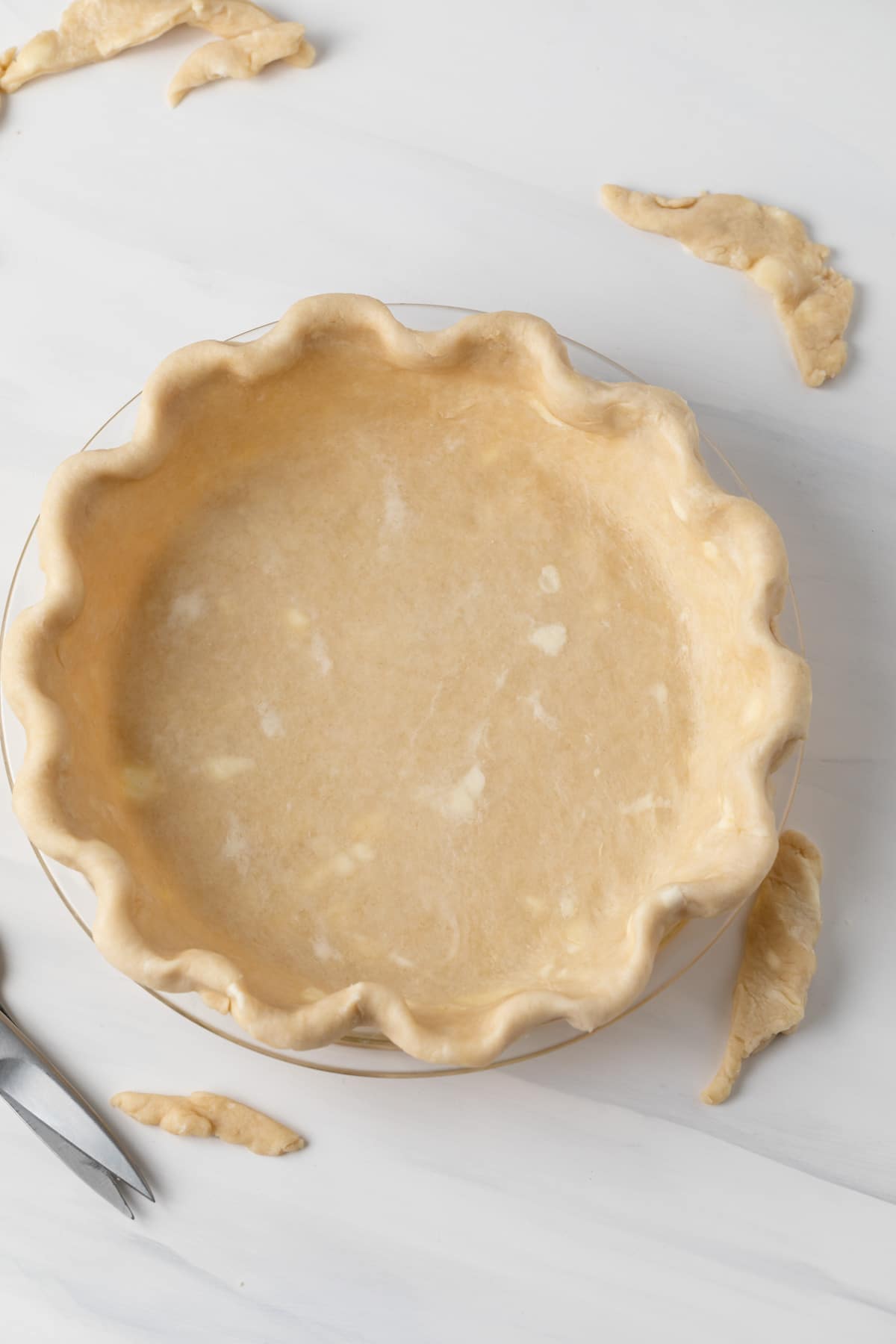 overhead of unbaked pie crust in glass pie pan