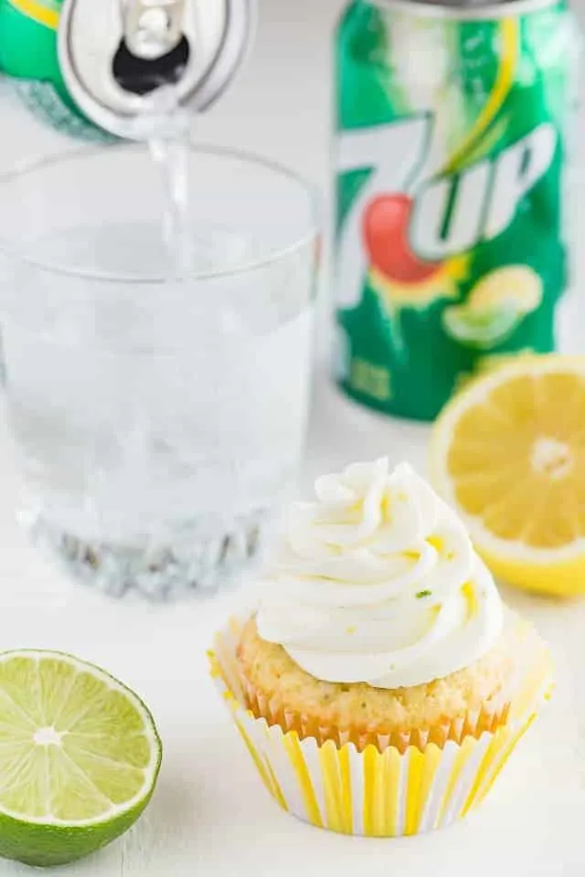 Angled view of lemon lime cupcakes with a can of 7up being poured into a glass.