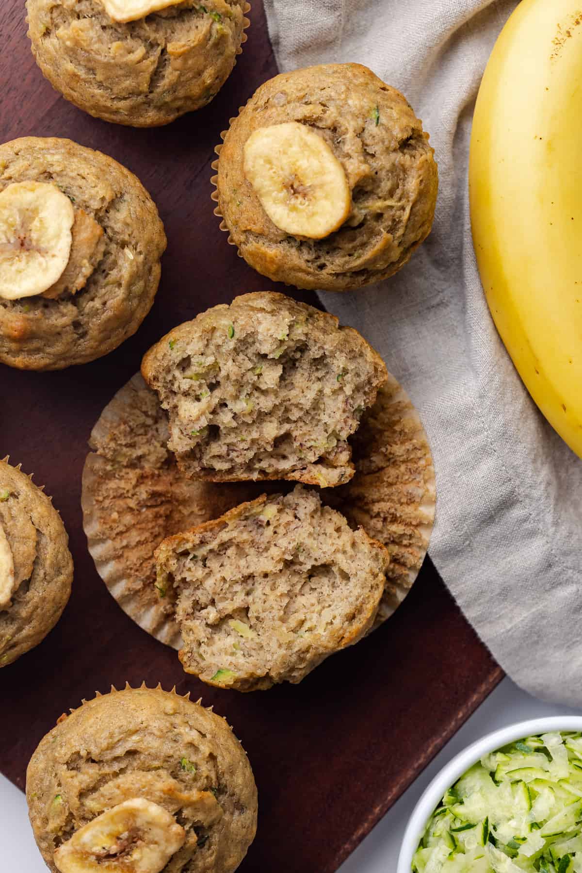 Overhead of zucchini banana muffins with one broken open.