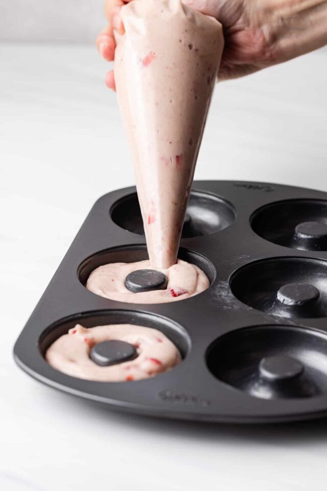 Strawberry cake donut batter poured into donut pan