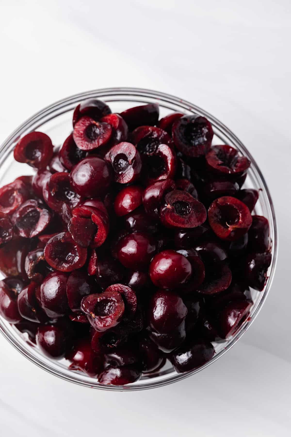 Pitted and halved dark red cherries in a glass bowl