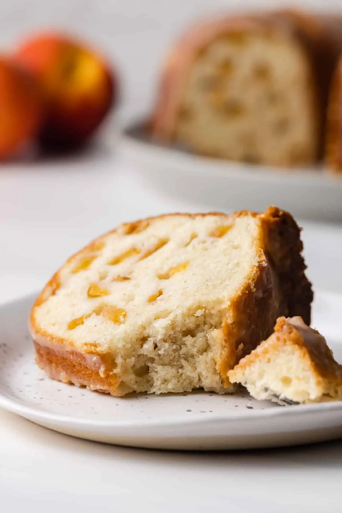 A slice of peach pound cake on a plate with a bite cut off