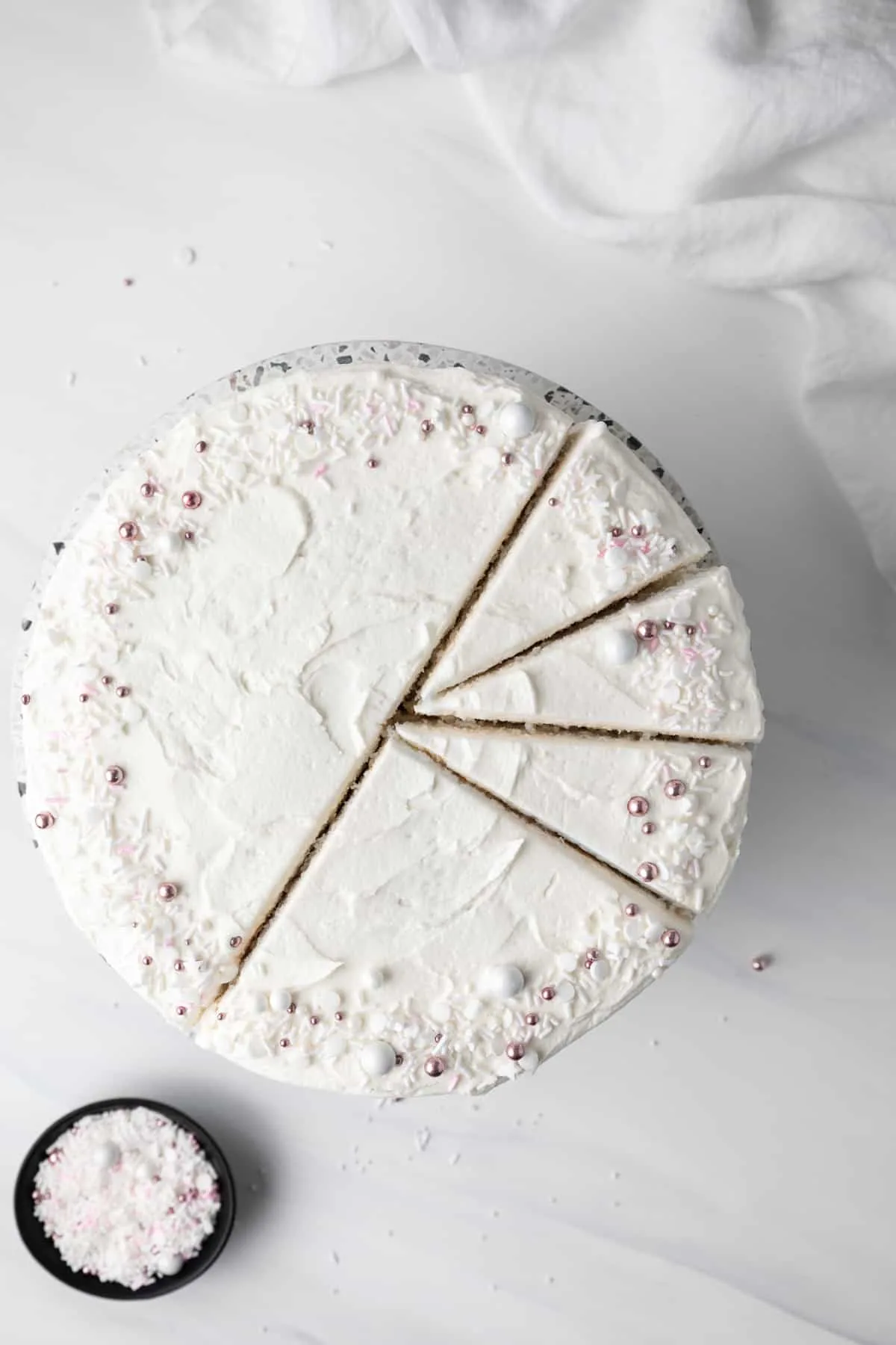 Frosted white cake, half cut into slices