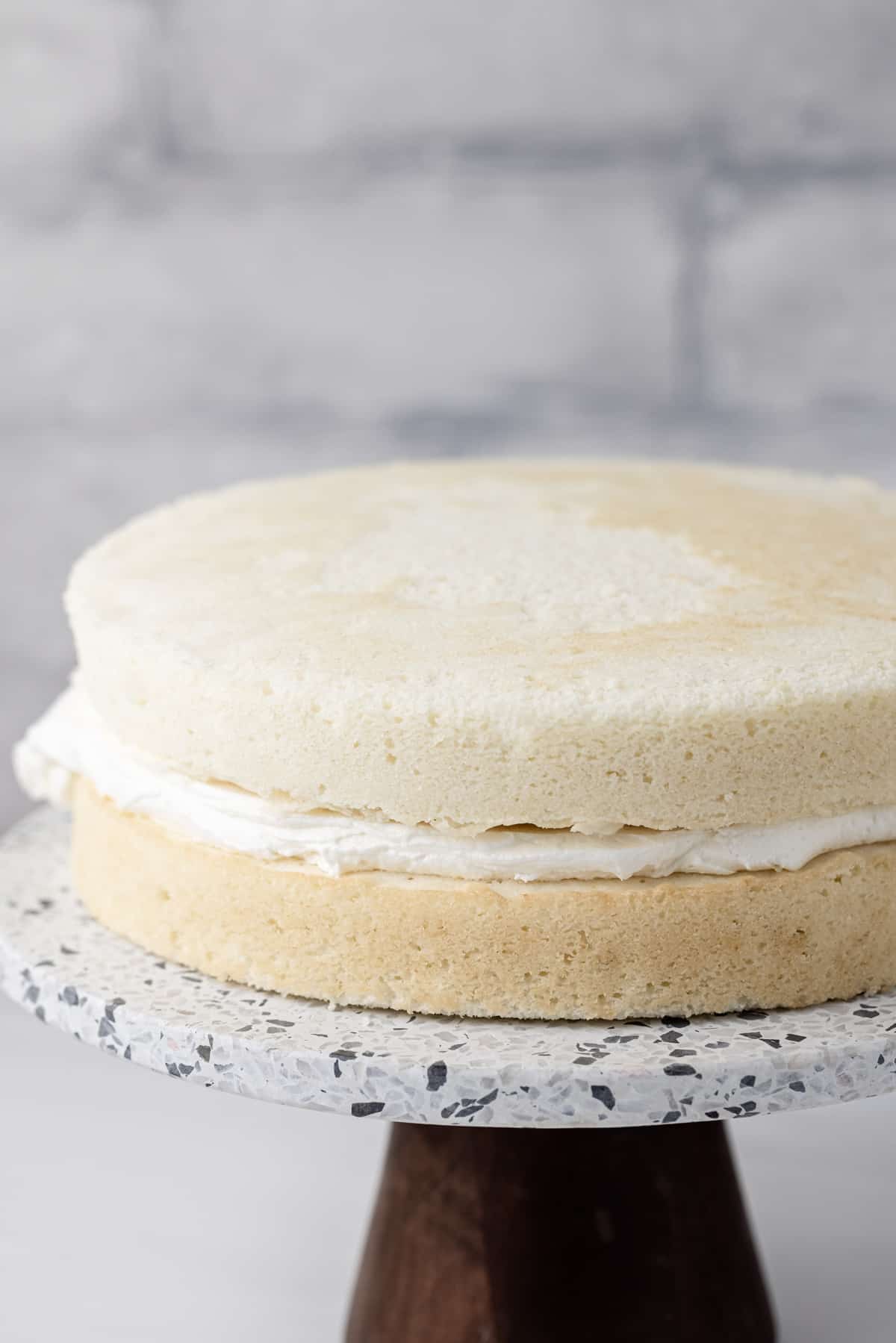 Two round moist white cakes with buttercream frosting in the center