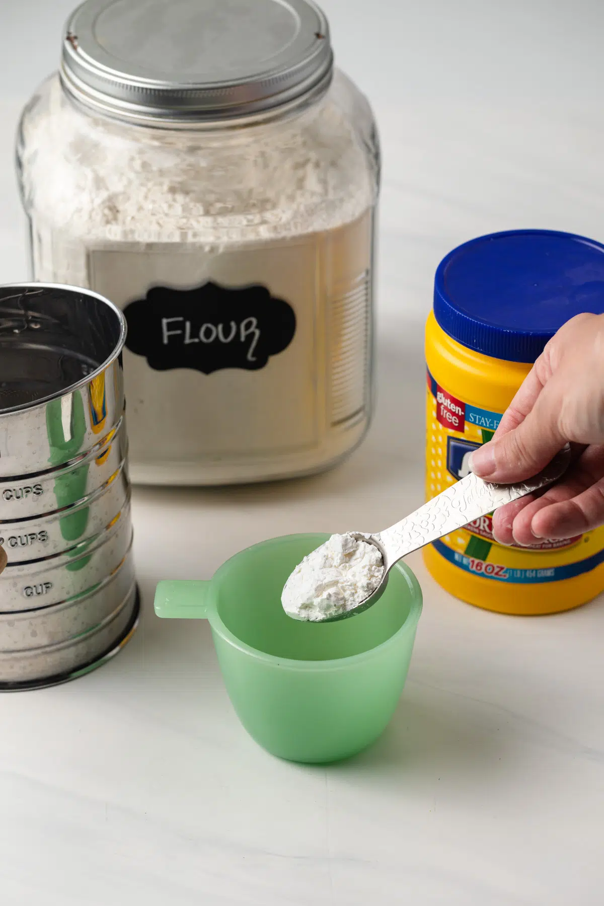 Cornstarch being added to measuring cup.