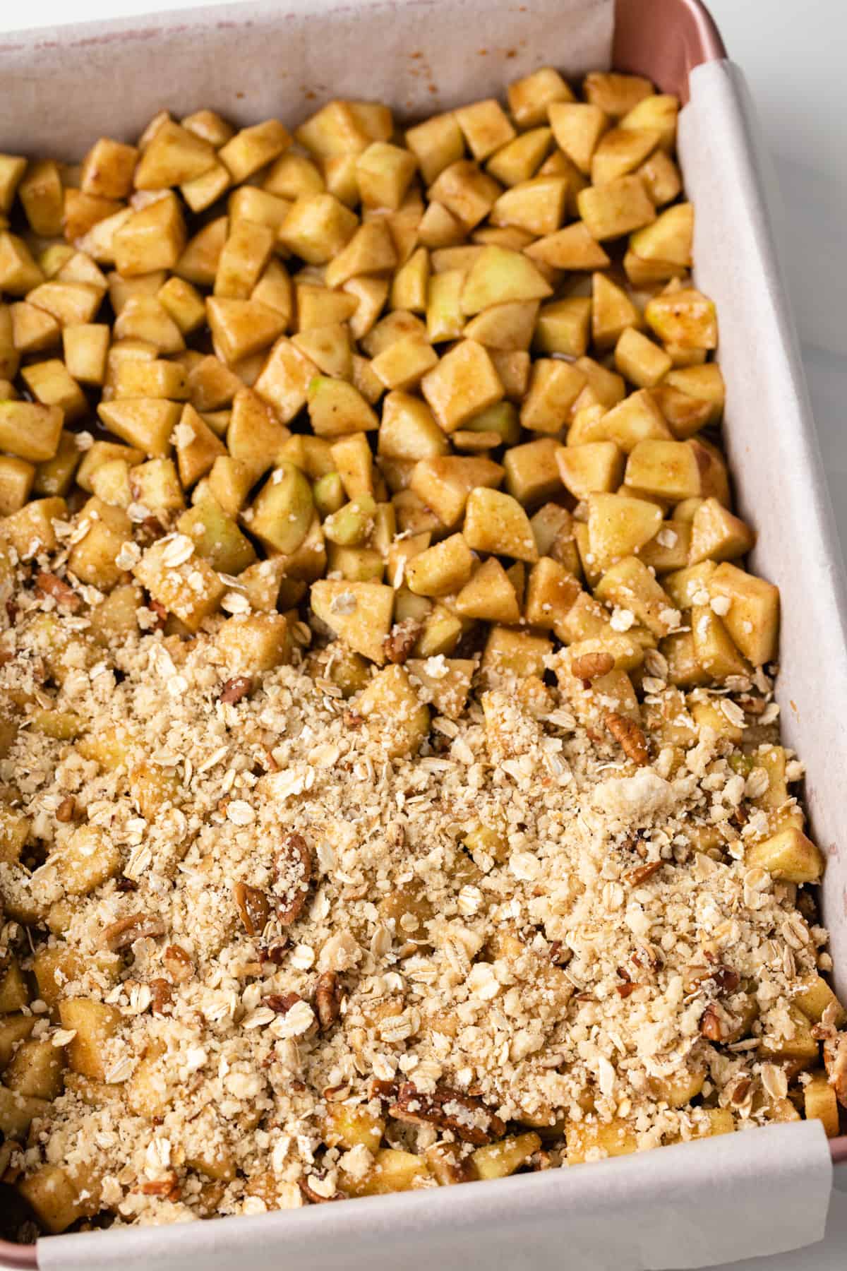 Streusel topping being layered over cinnamon apples