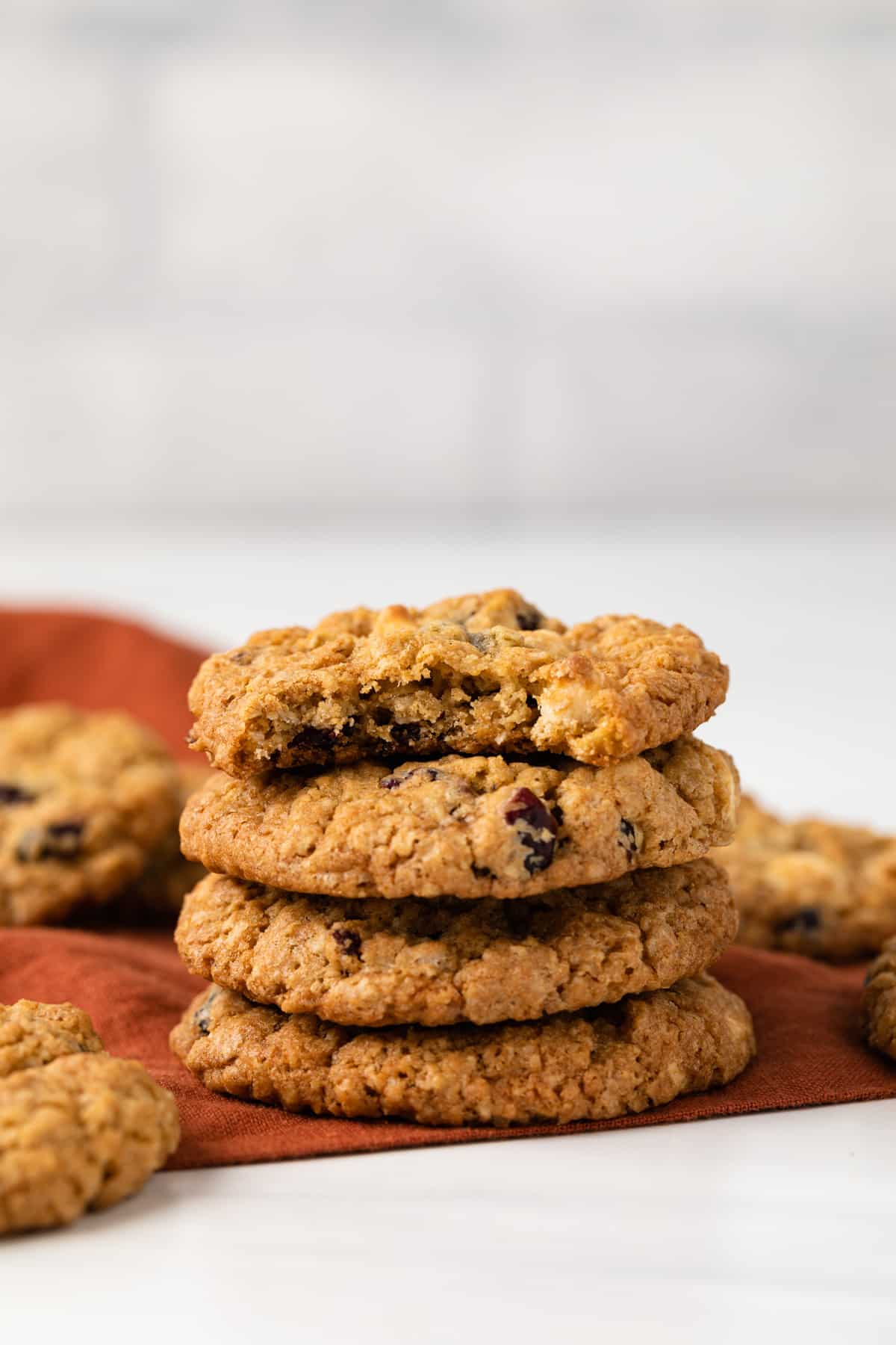 A stack of cranberry white chocolate oatmeal cookies, the top one with a bite missing