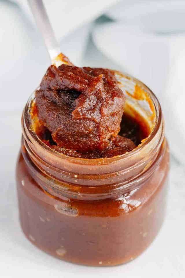 Close up image of Pumpkin Jam being scooped out of a glass jar with a spoon.
