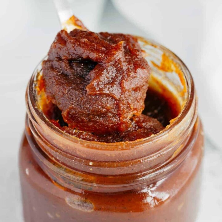 Close up image of Pumpkin Jam being scooped out of a glass jar with a spoon.