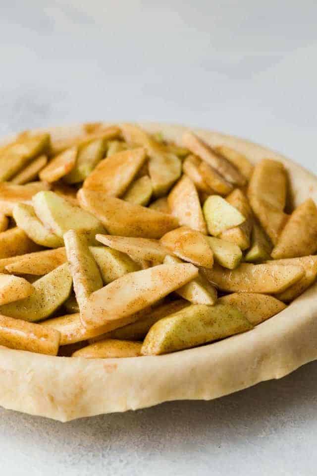 Apple filling layered in a pie crust ready to be baked.