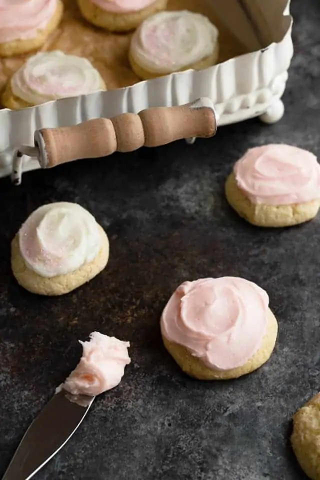 Frosted sour cream cookies next to a spreading knife with frosting on the tip.
