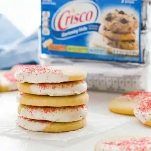 White chocolate peppermint cookies stacked on a piece of white parchment paper with a Crisco package behind it.