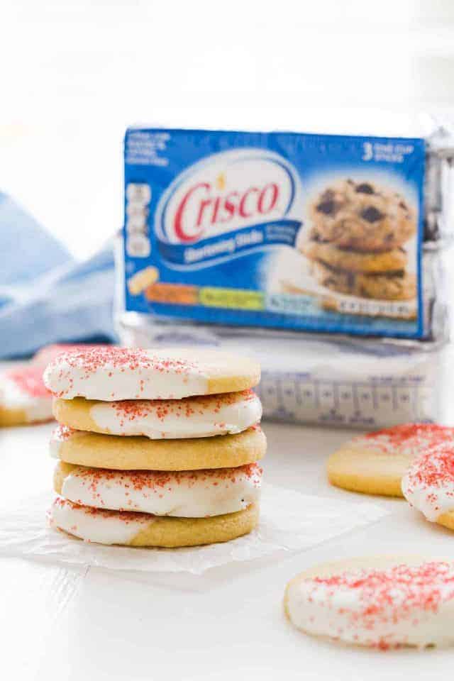 White chocolate peppermint cookies stacked on a piece of white parchment paper with a Crisco package behind it.