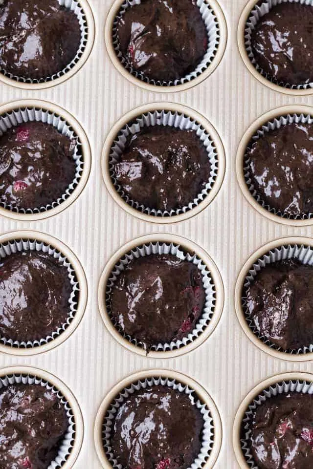 Double chocolate raspberry muffin batter in a gold muffin pan.