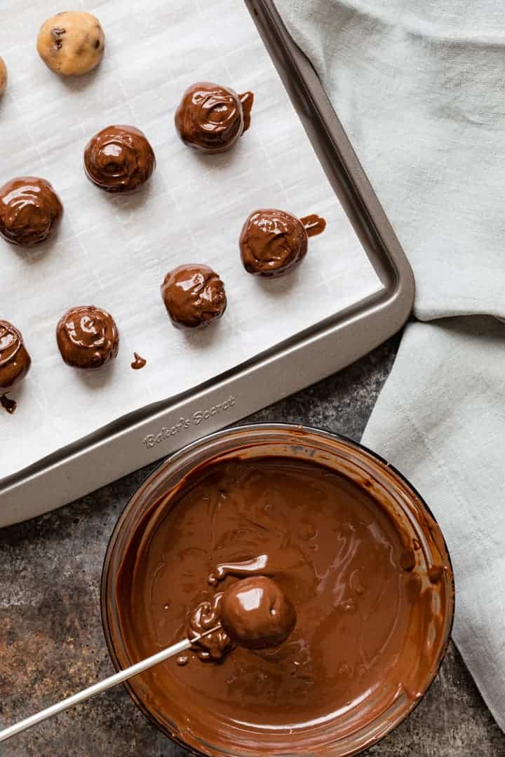 cookie dough balls being dipped in melted chocolate