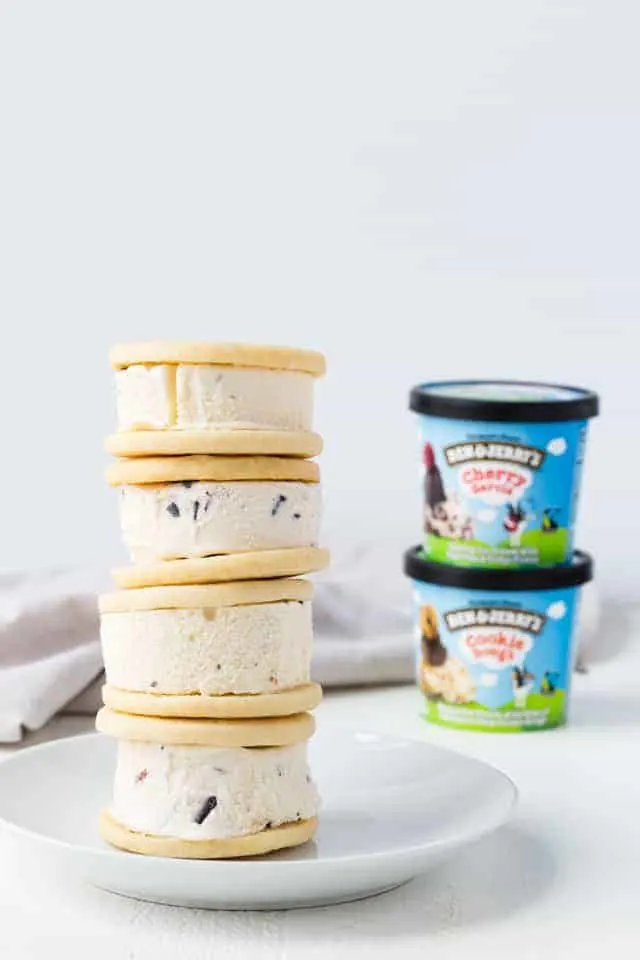 Ice Cream Sandwich Cookies Soft ice cream sandwich cookies stacked four high on a white plate next to cartons of Ben & Jerry's Cups.