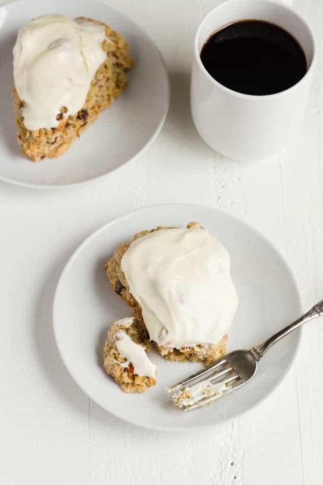A Carrot Cake Scone on a white plate with a fork taking a bite out.