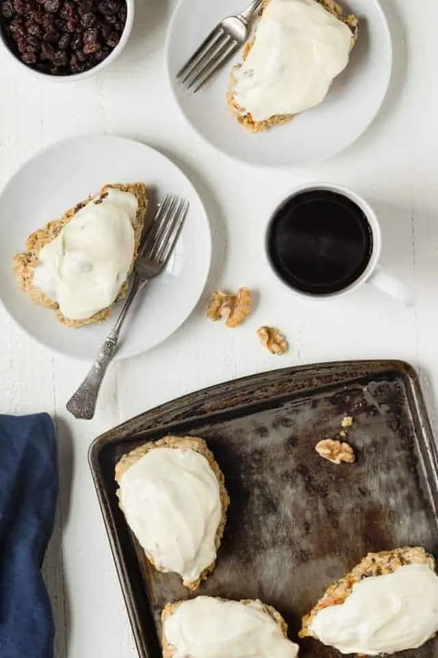 Overhead view of Carrot Cake Scones on white plates and a baking sheet.