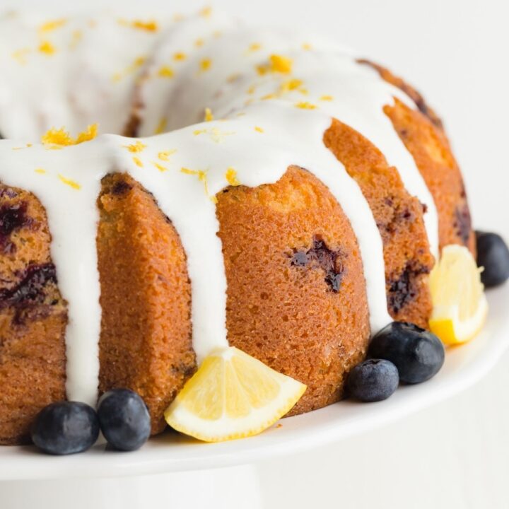 Lemon blueberry bundt cake on a white cake stand.