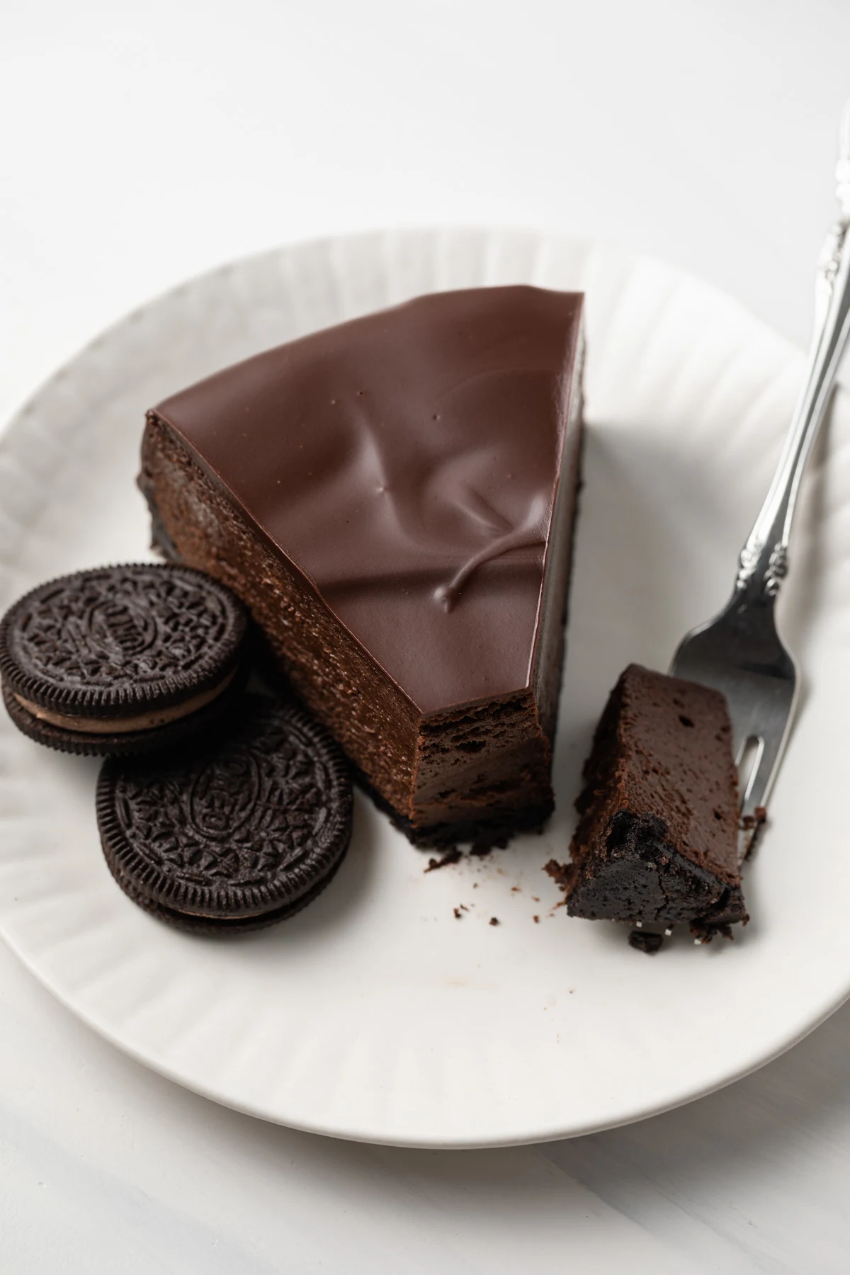 A slice of creamy triple chocolate cheesecake with a fork taking a bite out.