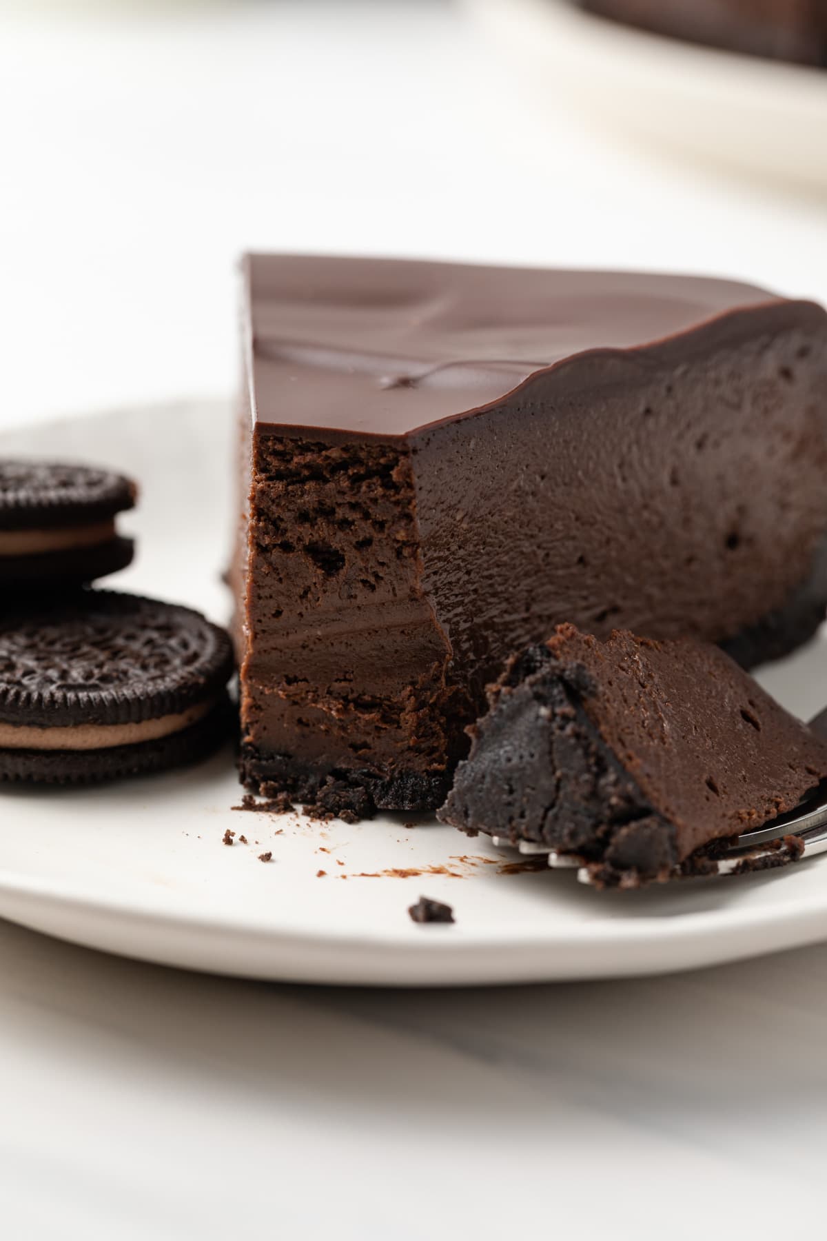 A slice of triple chocolate cheesecake on a white plate.