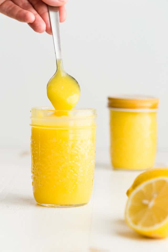 Lemon curd being spooned out of a jar.