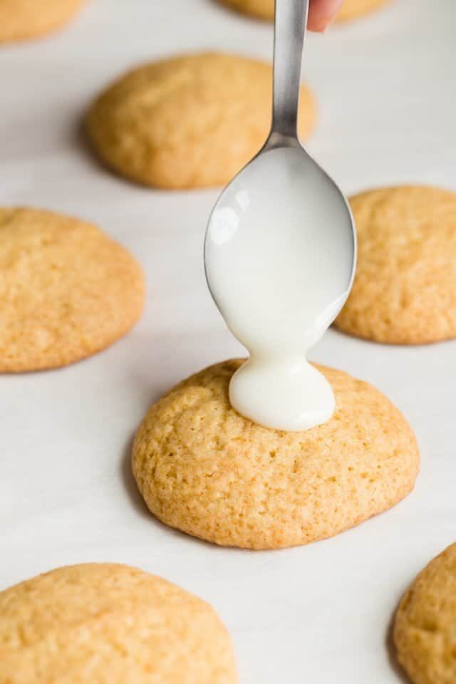 glaze being spooned over lemon cookies