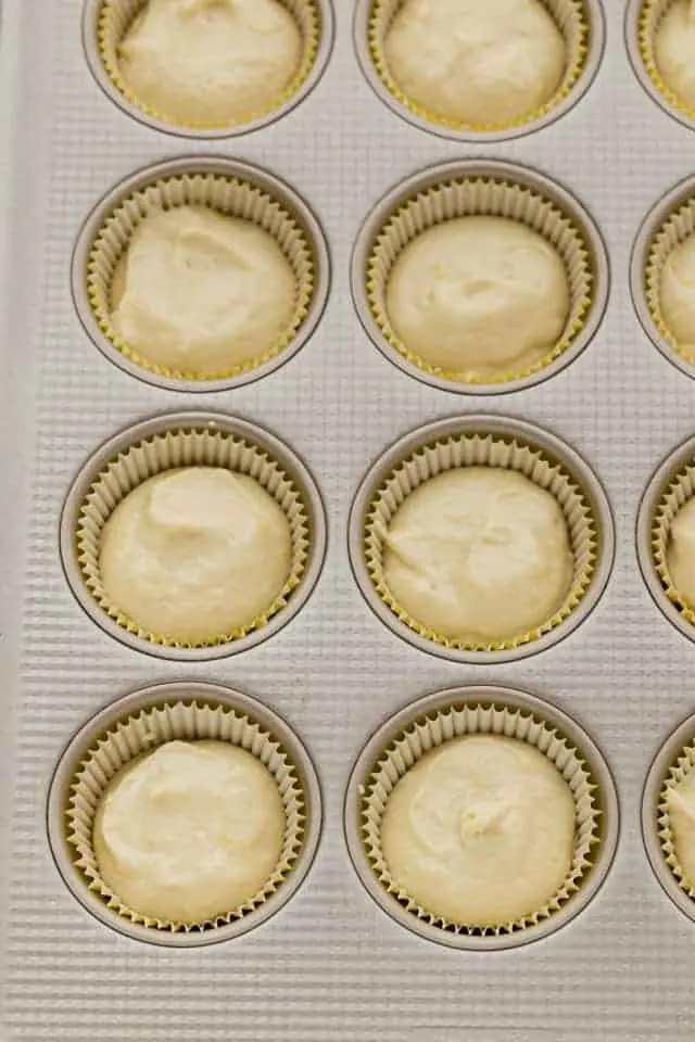 Lemon cupcake batter in a muffin pan lined with cupcake liners.