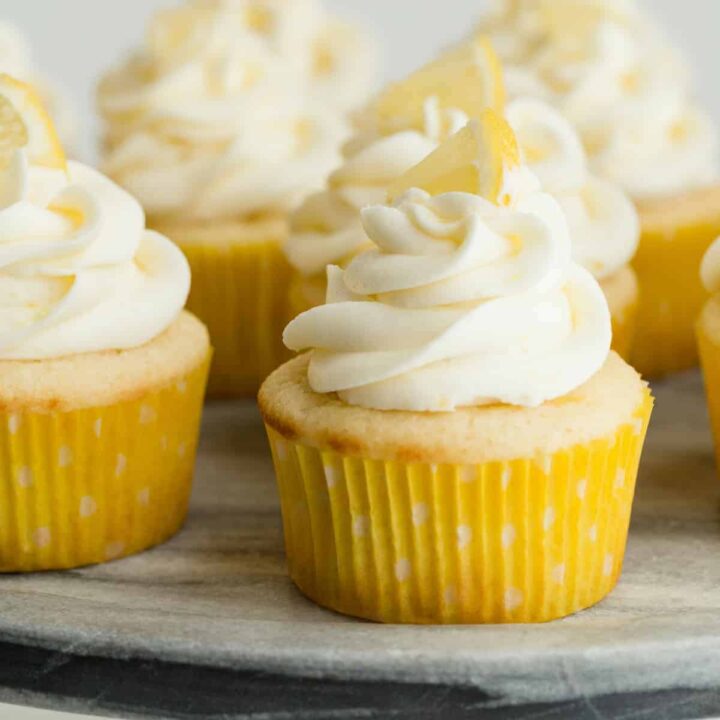 Lemon cupcakes with lemon frosting on a gray marble platter.