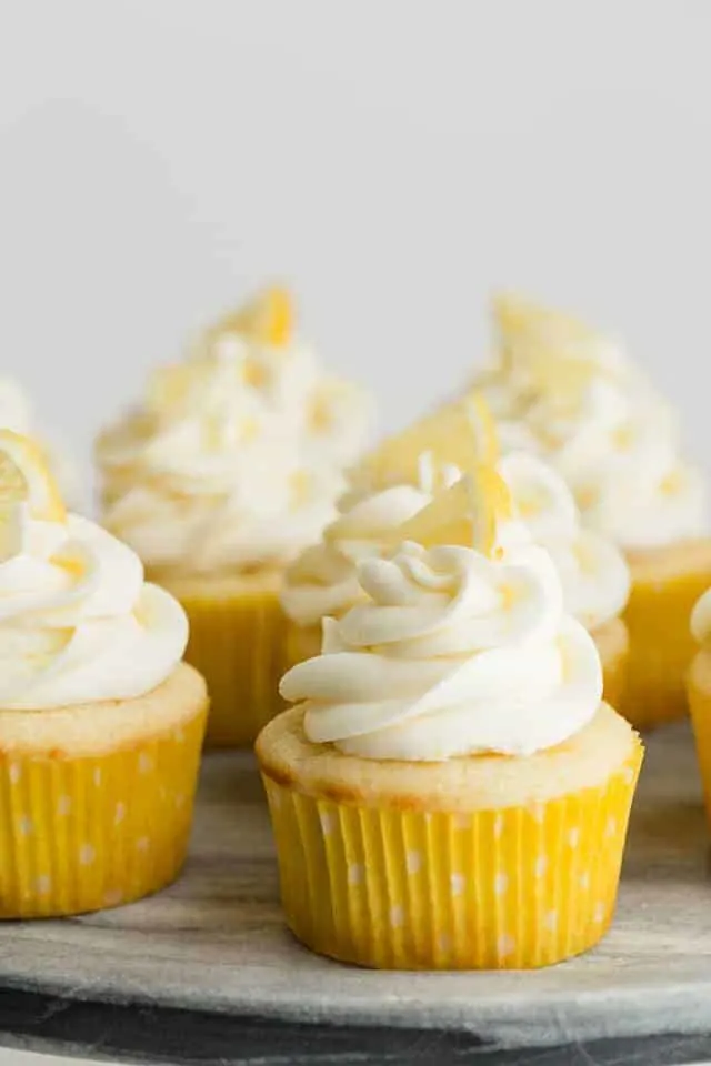 Lemon cupcakes with lemon frosting on a gray marble platter.