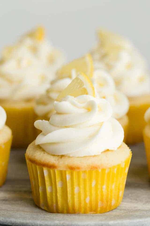 Lemon Cupcakes topped with lemon frosting and a tiny lemon piece on top.