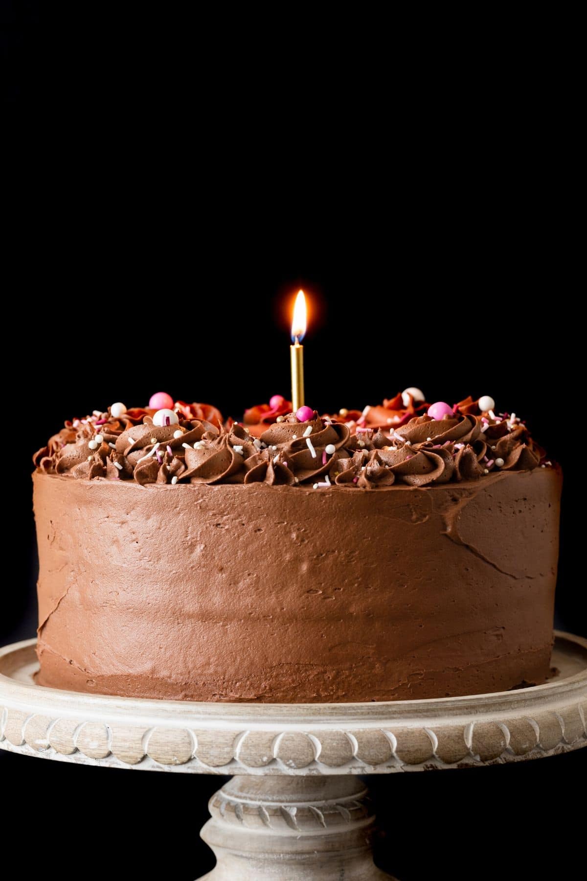 Classic Birthday Cake on a marble cake stand with a wooden base