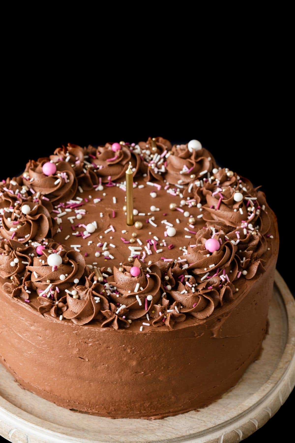 Angled view of homemade birthday cake with chocolate frosting and sprinkles.