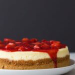 cheesecake topped with strawberry sauce on white plate